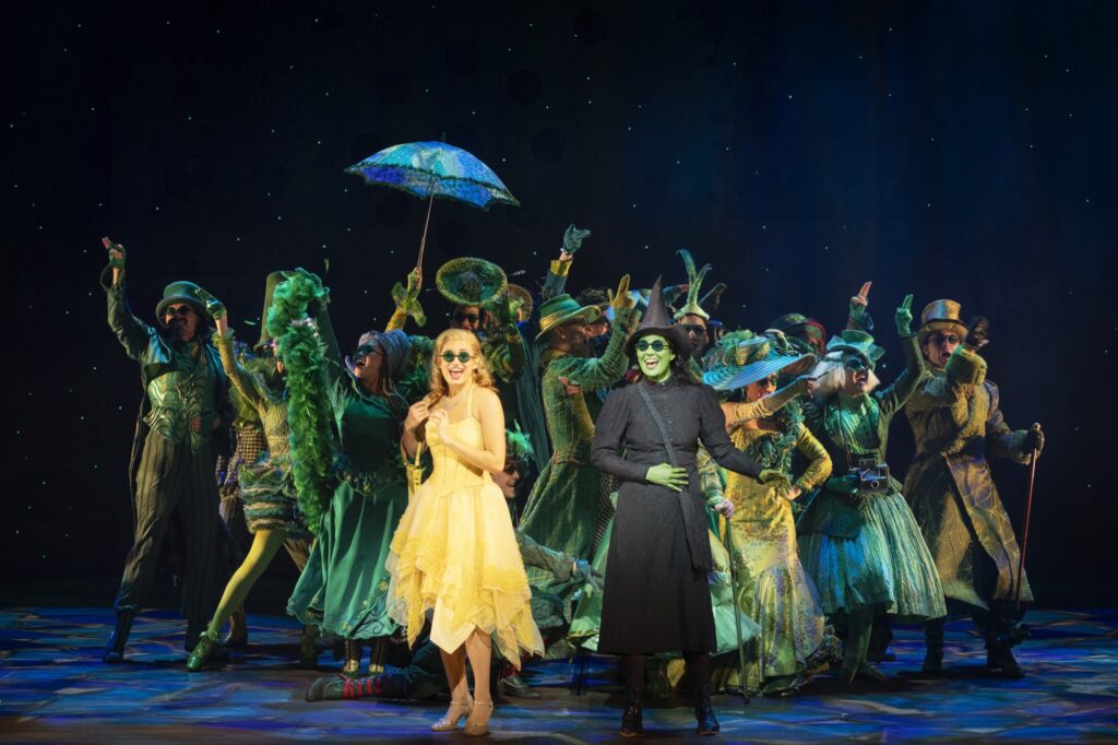 Glinda and Elphaba with the ensemble, dressed in green. 